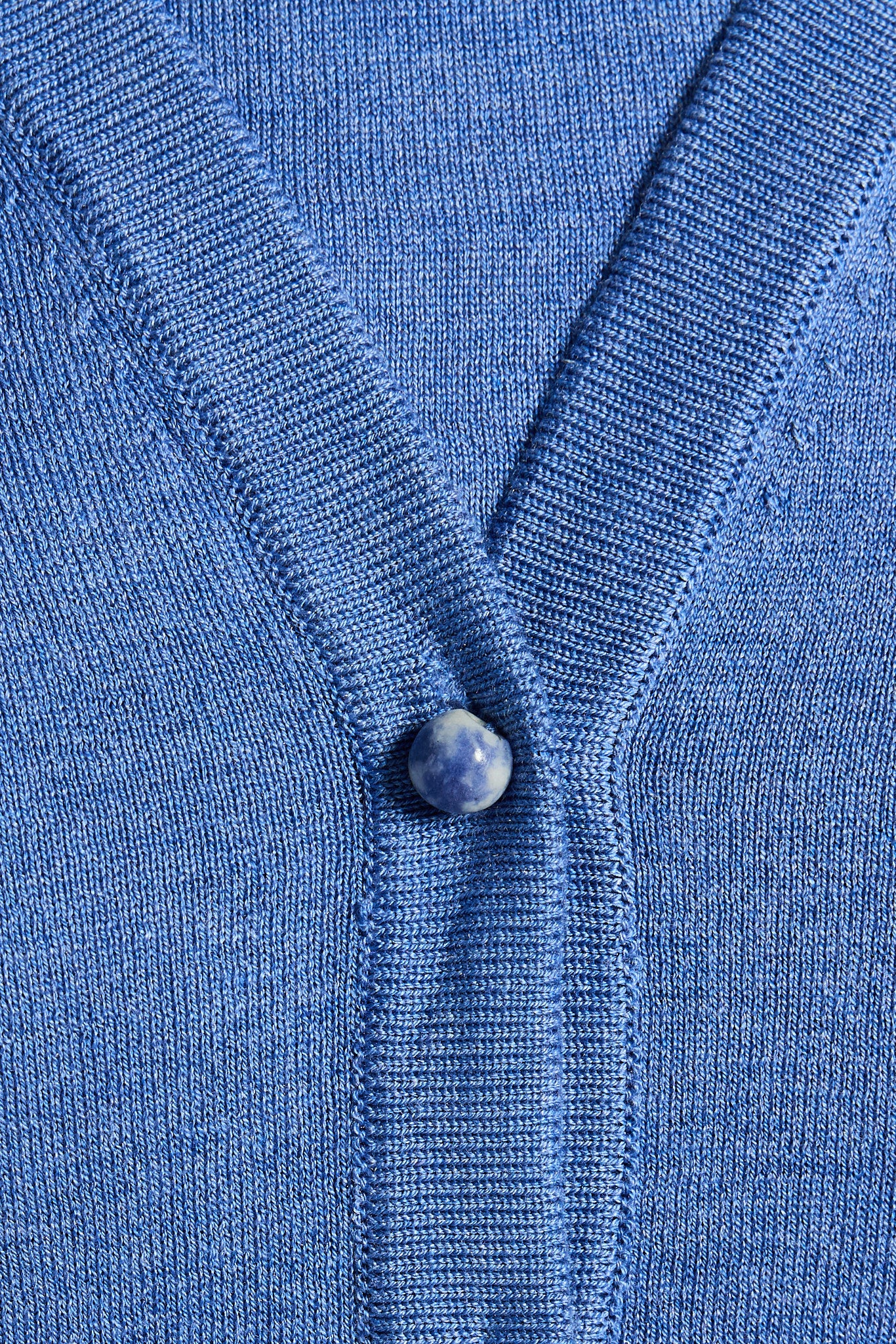 Close-up of a blue cardigan with a Blue Spot Jasper button 