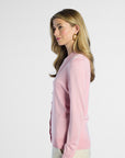 side profile of a woman wearing a pink silk cardigan against a white background