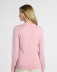 back profile shot of a woman wearing a pink silk cardigan against a white background