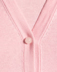Close-up of a pink cardigan with a gemstone button on a matching pink background
