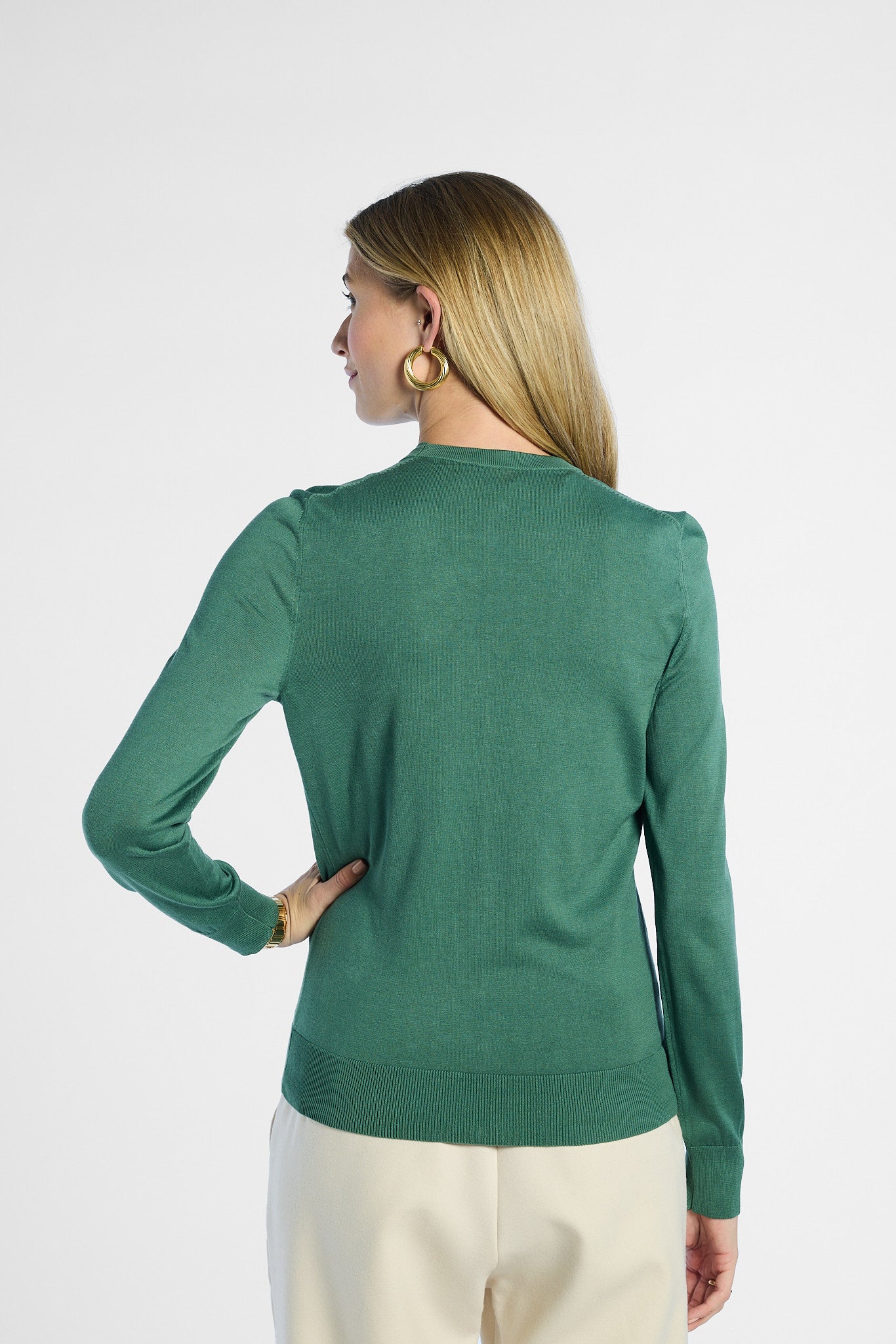 back profile of a woman wearing a green silk cardigan on a white background