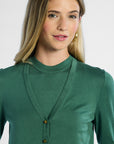 Woman wearing a green silk cardigan with a plain background