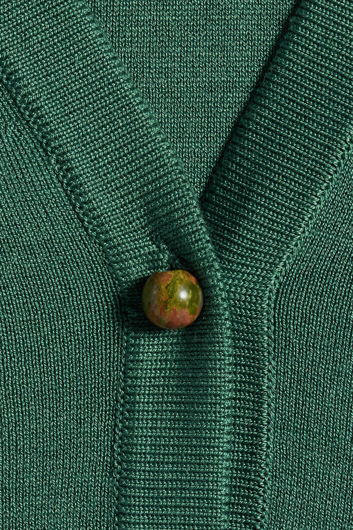 Close-up of a green silk cardigan with unakite gemstone buttons 