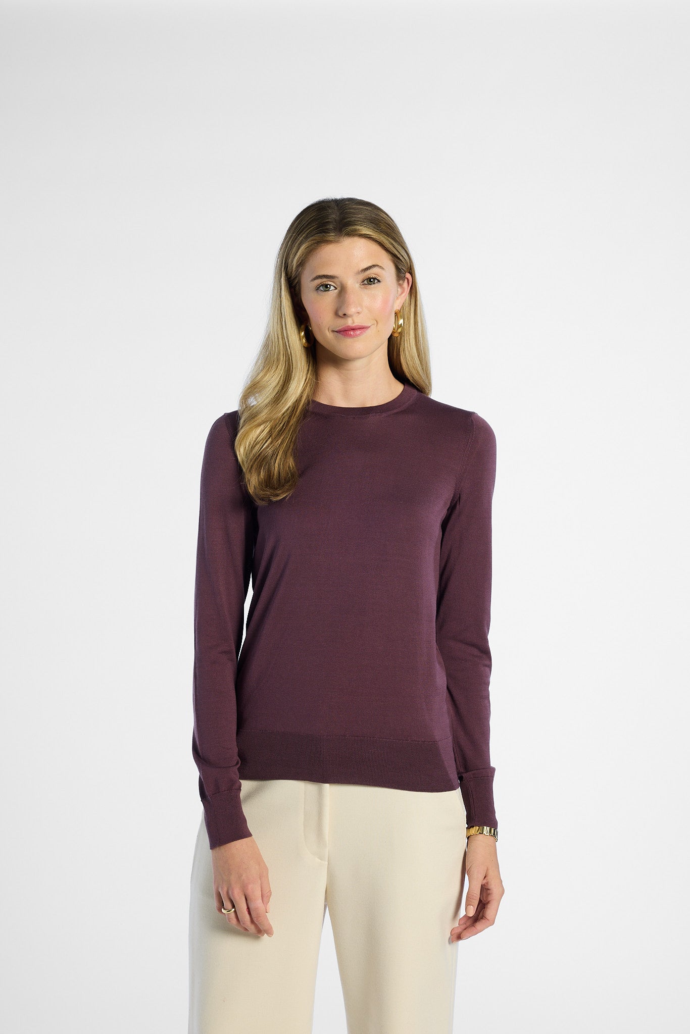 Woman wearing a purple long-sleeve top against a white background