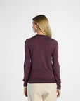 back profile of a Woman wearing a purple sweater and beige pants on a white background