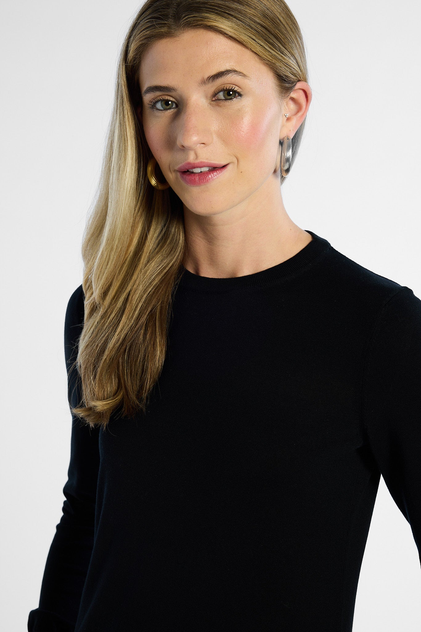 close up shot of a woman wearing a black long-sleeve top against a white background