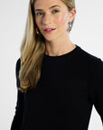 close up shot of a woman wearing a black long-sleeve top against a white background