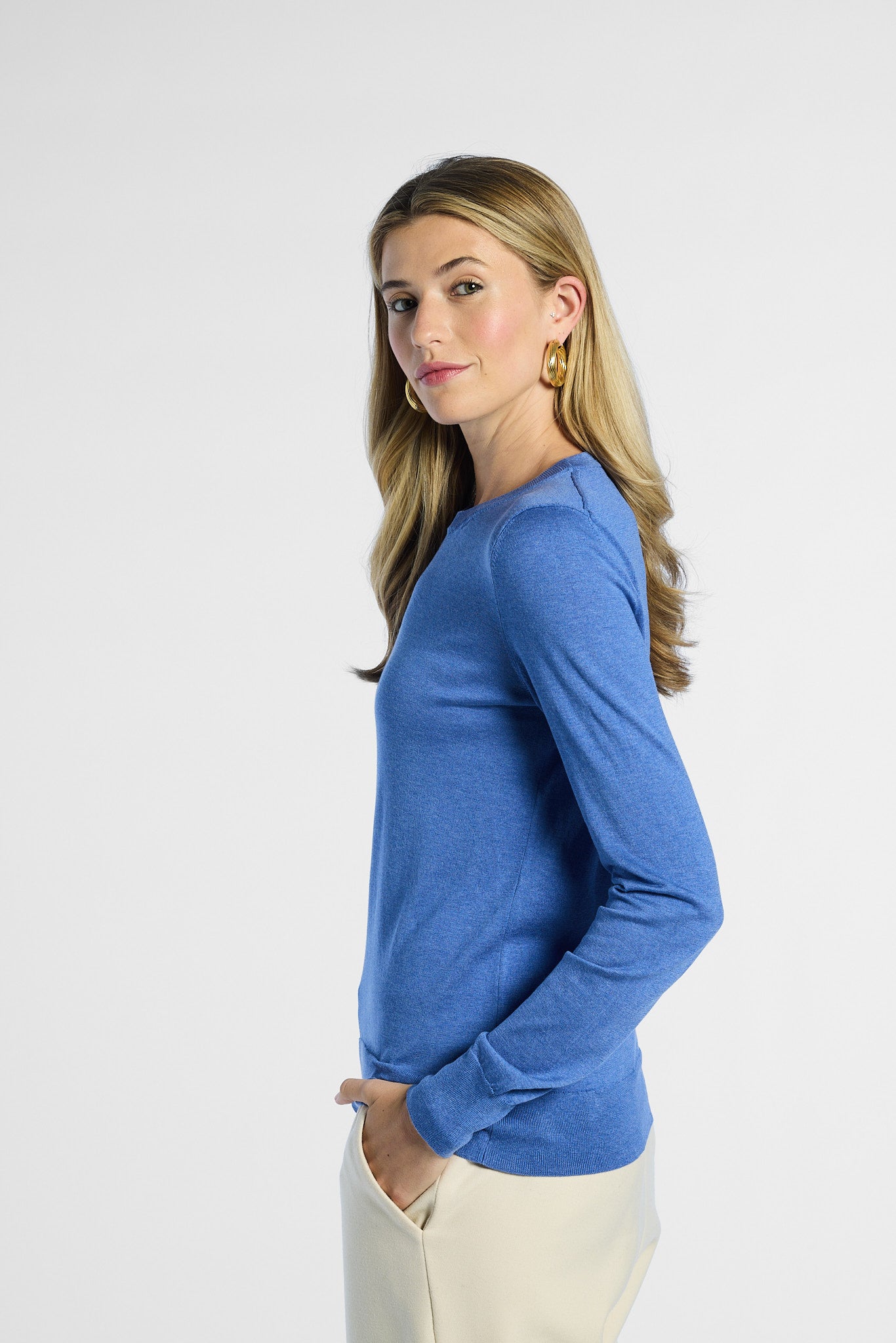 side profile of a woman wearing a blue sweater on a white background