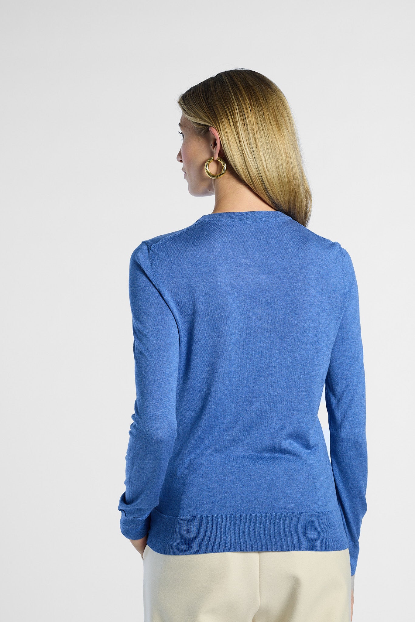 back profile of a woman wearing a blue sweater against a white background