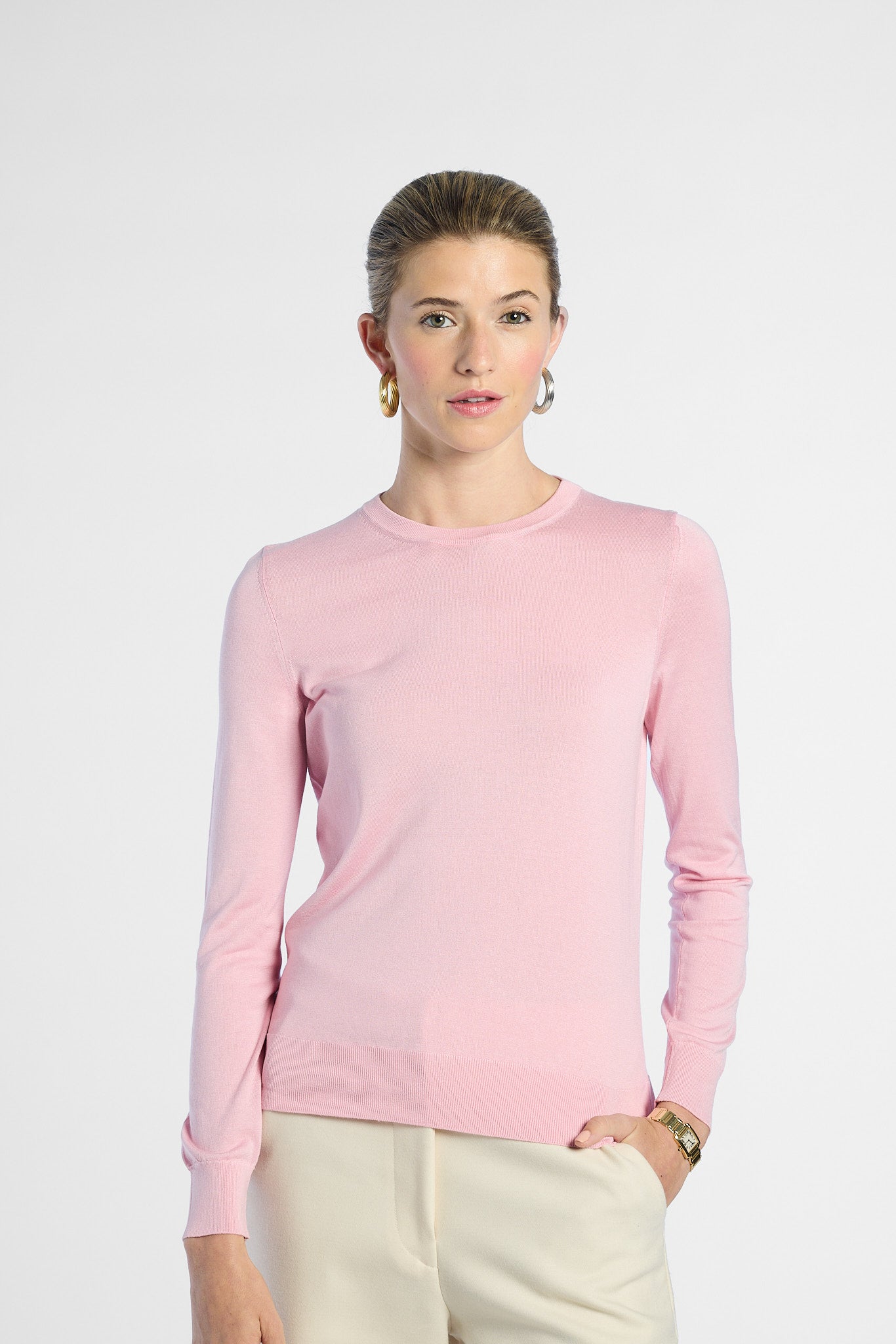 Woman wearing a pink silk crewneck on a white background