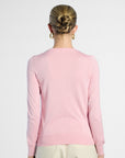 Person wearing a pink silk sweater with a plain background