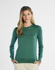 Woman wearing a green silk sweater on a white background