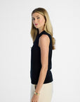 side profile of a Woman wearing a black sleeveless silk top and beige pants on a white background
