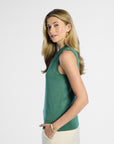side profile of a woman wearing a green sleeveless silk top against a white background