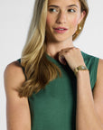 close up of a woman wearing a green sleeveless silk top with a plain background