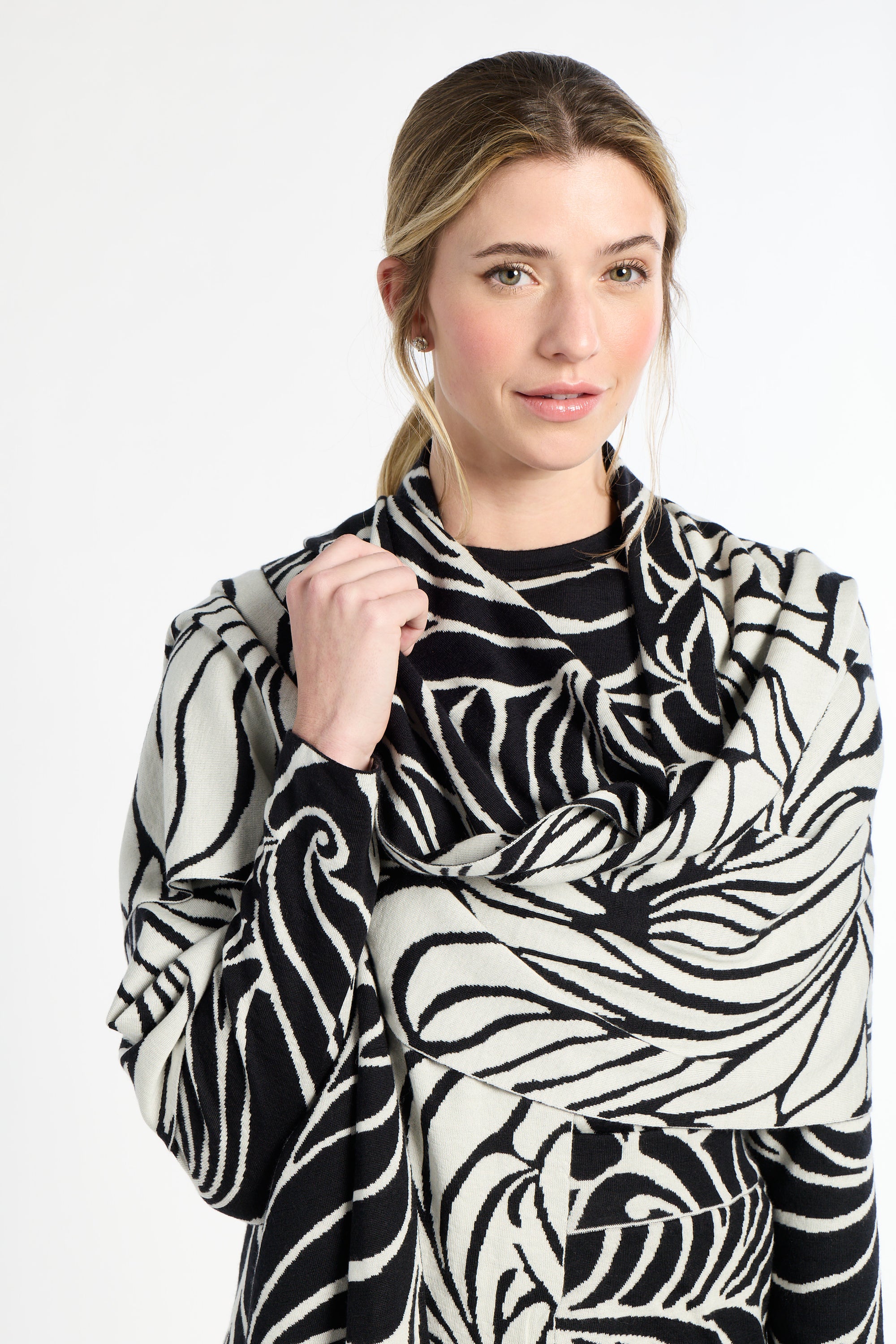 Woman wearing a black and white patterned scarf on a plain background