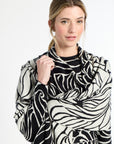 Woman wearing a black and white patterned scarf on a plain background
