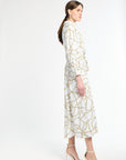 Woman wearing a white dress with gold pattern and white heels on a white background