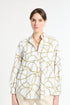 Woman modeling white and gold patterned top against a white background
