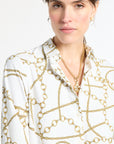 Woman modeling a white collared top with gold jewelry