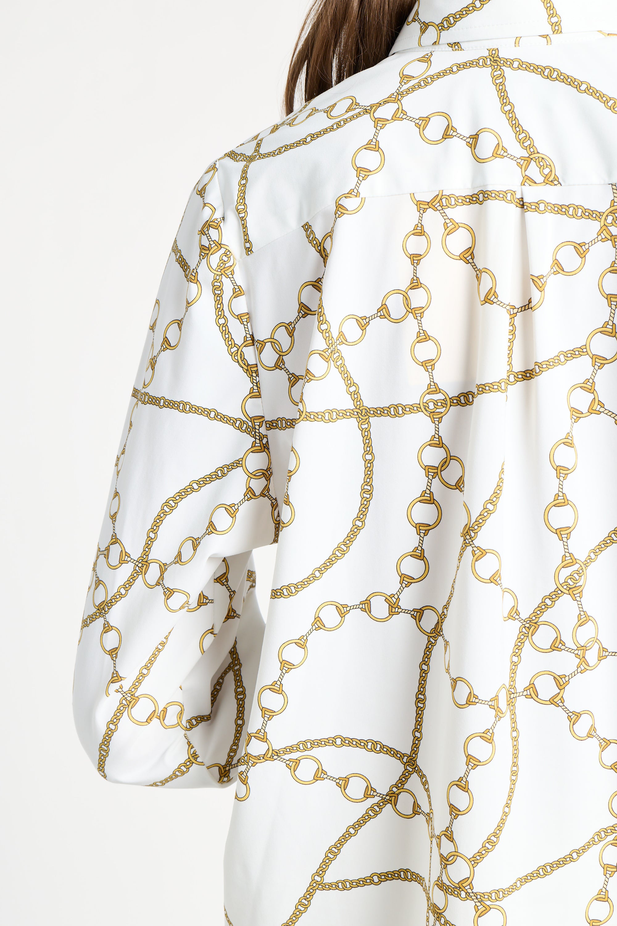 Woman wearing a long sleeve white blouse with gold details