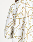 Woman wearing a long sleeve white blouse with gold details