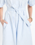 Light blue and white striped dress with a tie waist, worn by a person.