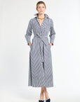 Woman wearing a long blue and white striped dress on a white background