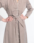 Woman wearing a long, striped dress with a belt on a white background