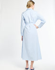 Woman wearing a light blue striped dress against a white background
