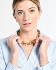 Woman wearing a gold chain necklace against a white background
