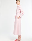 Woman wearing a light pink dress with a belt on a white background