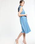Woman walking in blue dress and white heels against a white background
