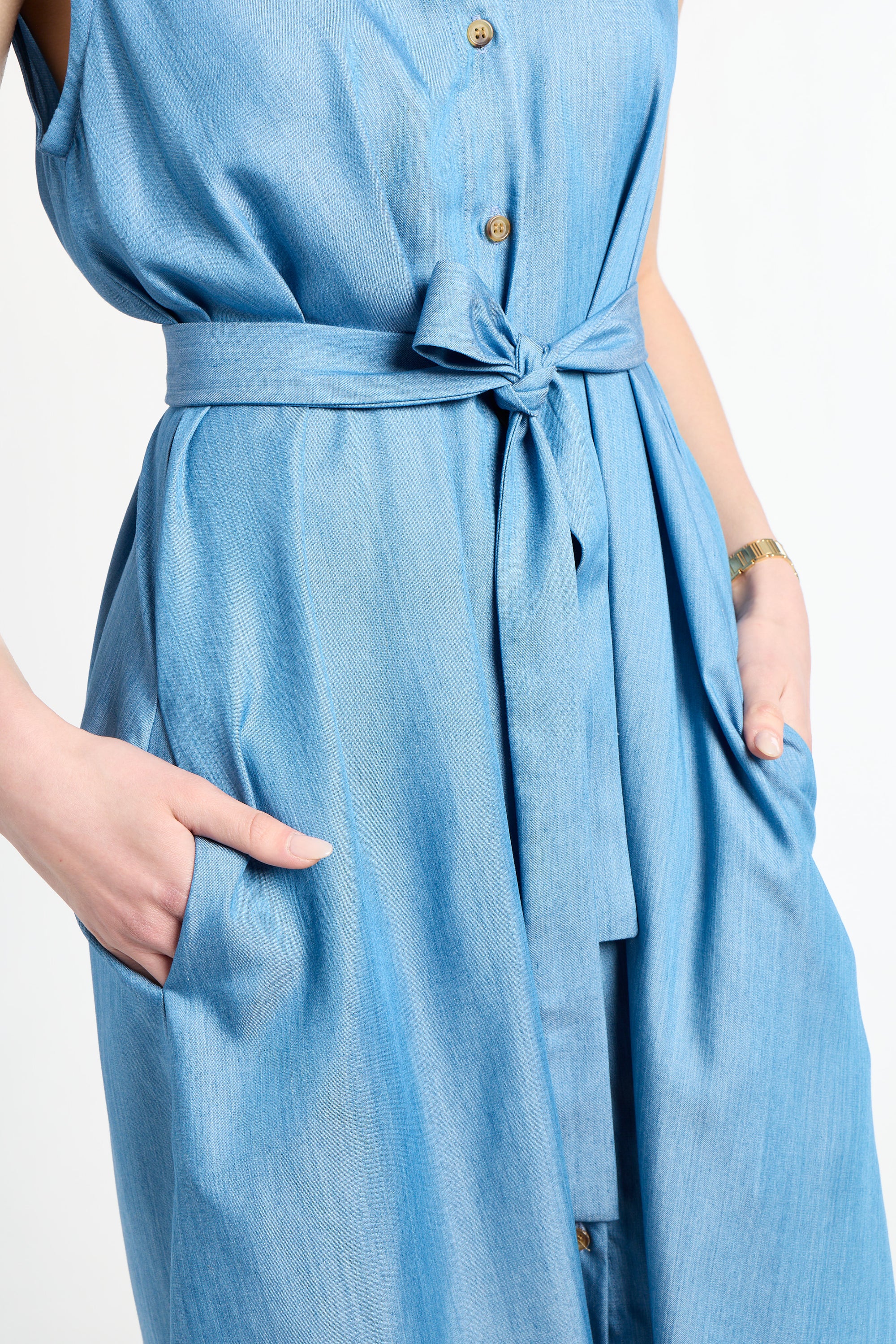 Woman wearing a light blue dress with buttons and tie around the waste