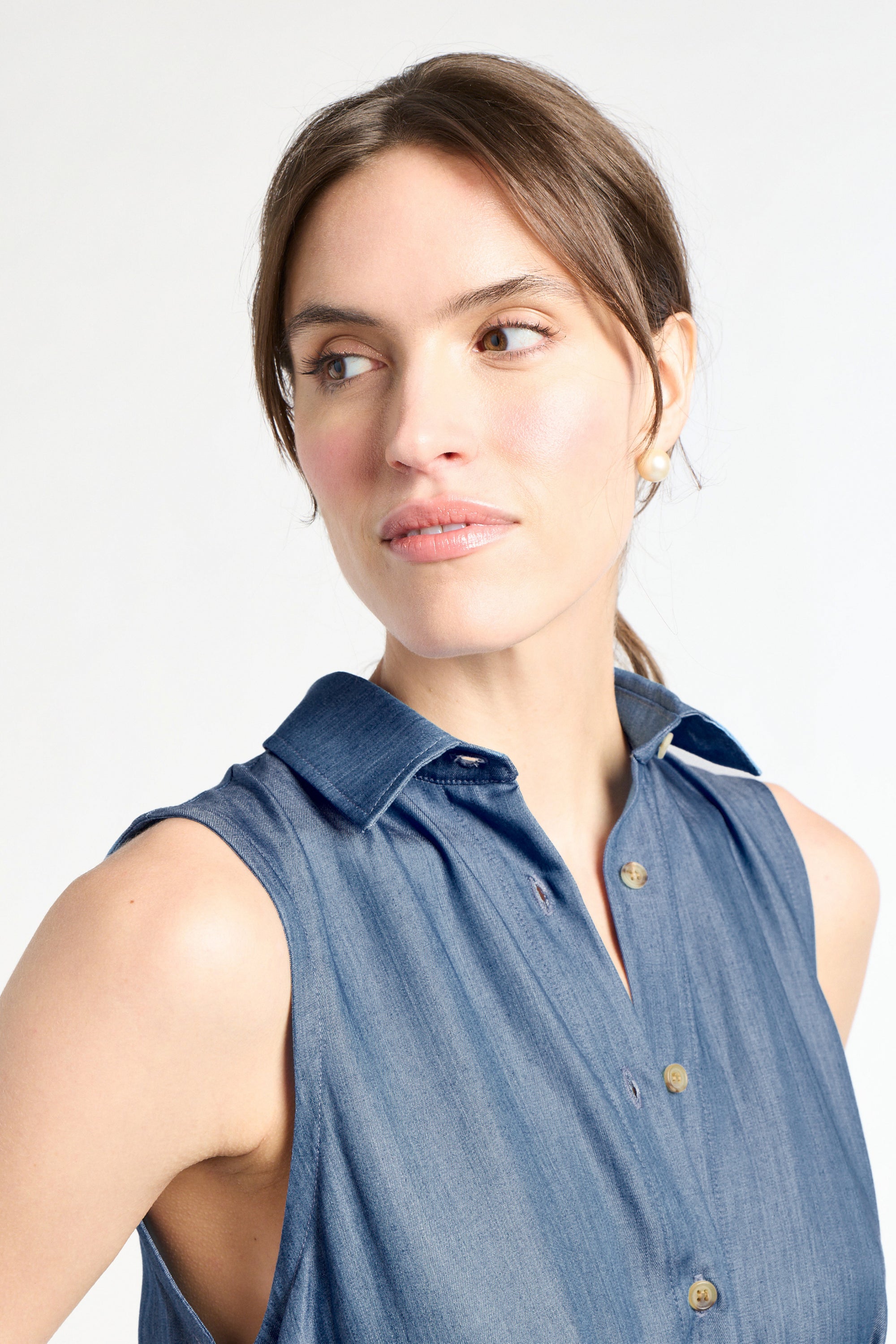 Woman wearing a sleeveless denim shirt against a white background