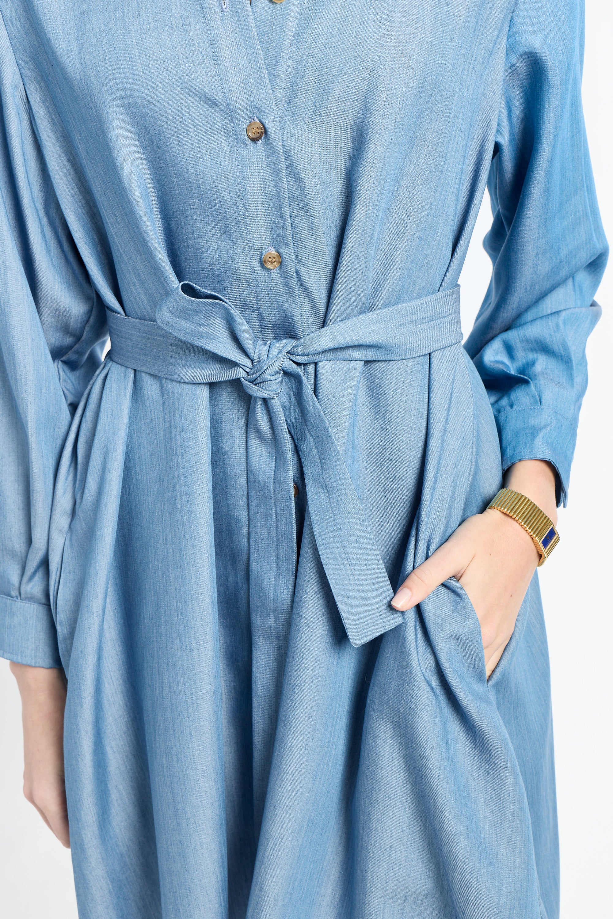 Woman modeling a blue dress with tie around waste