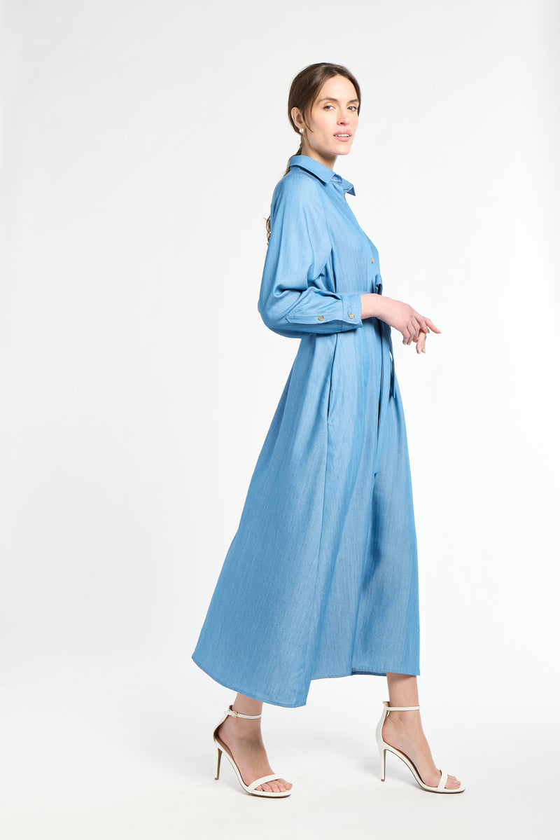 Woman wearing a long blue dress and white heels on a white background
