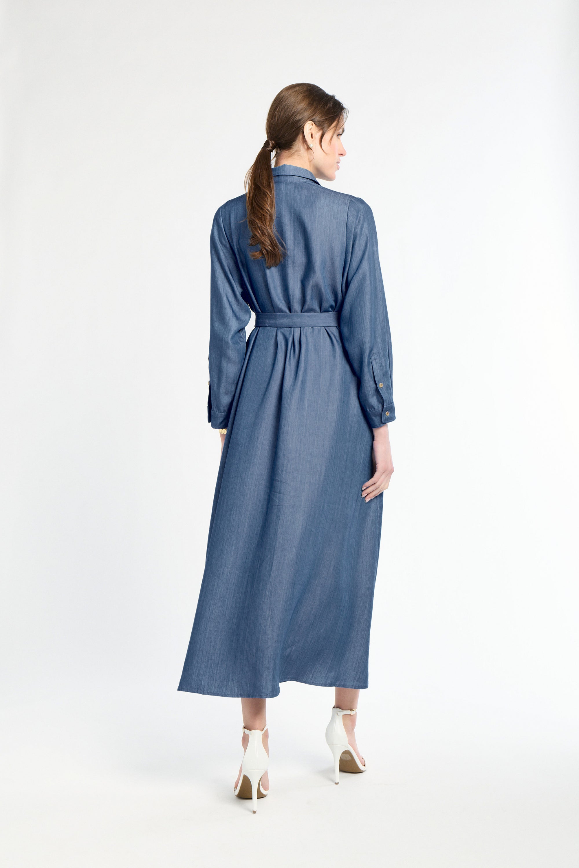 Woman wearing a blue dress standing against a white background