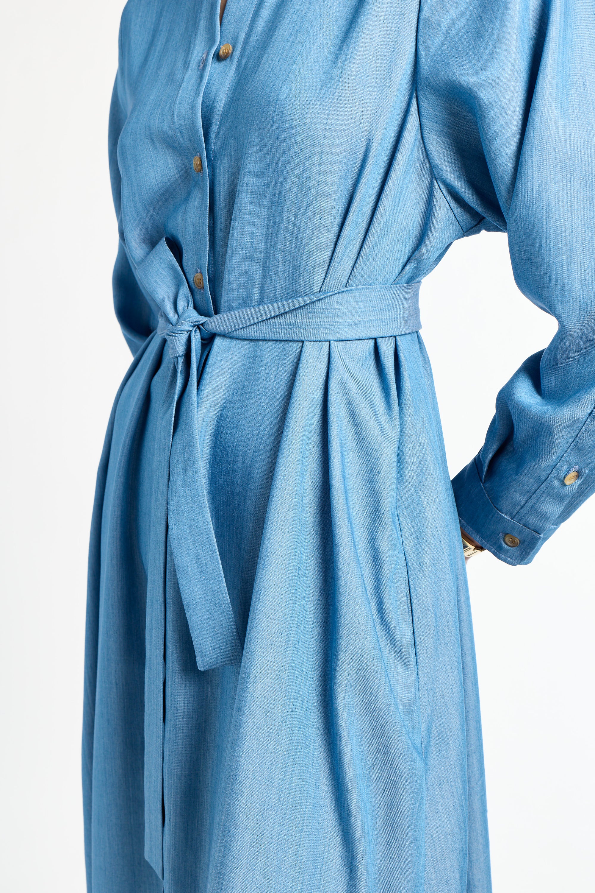 long sleeve blue dress with ribbon around waist against a white background