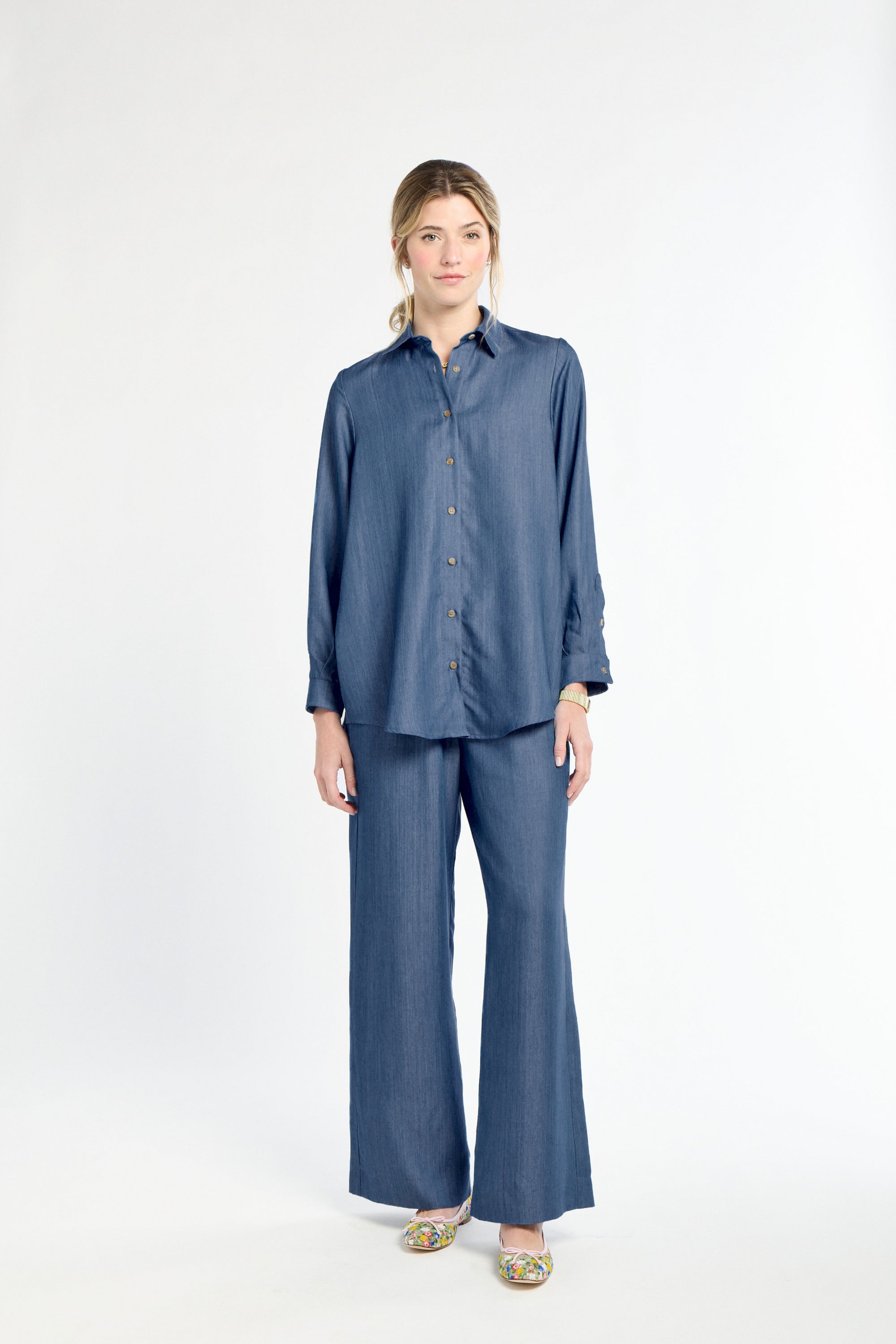 Woman wearing a blue shirt and pants on a white background
