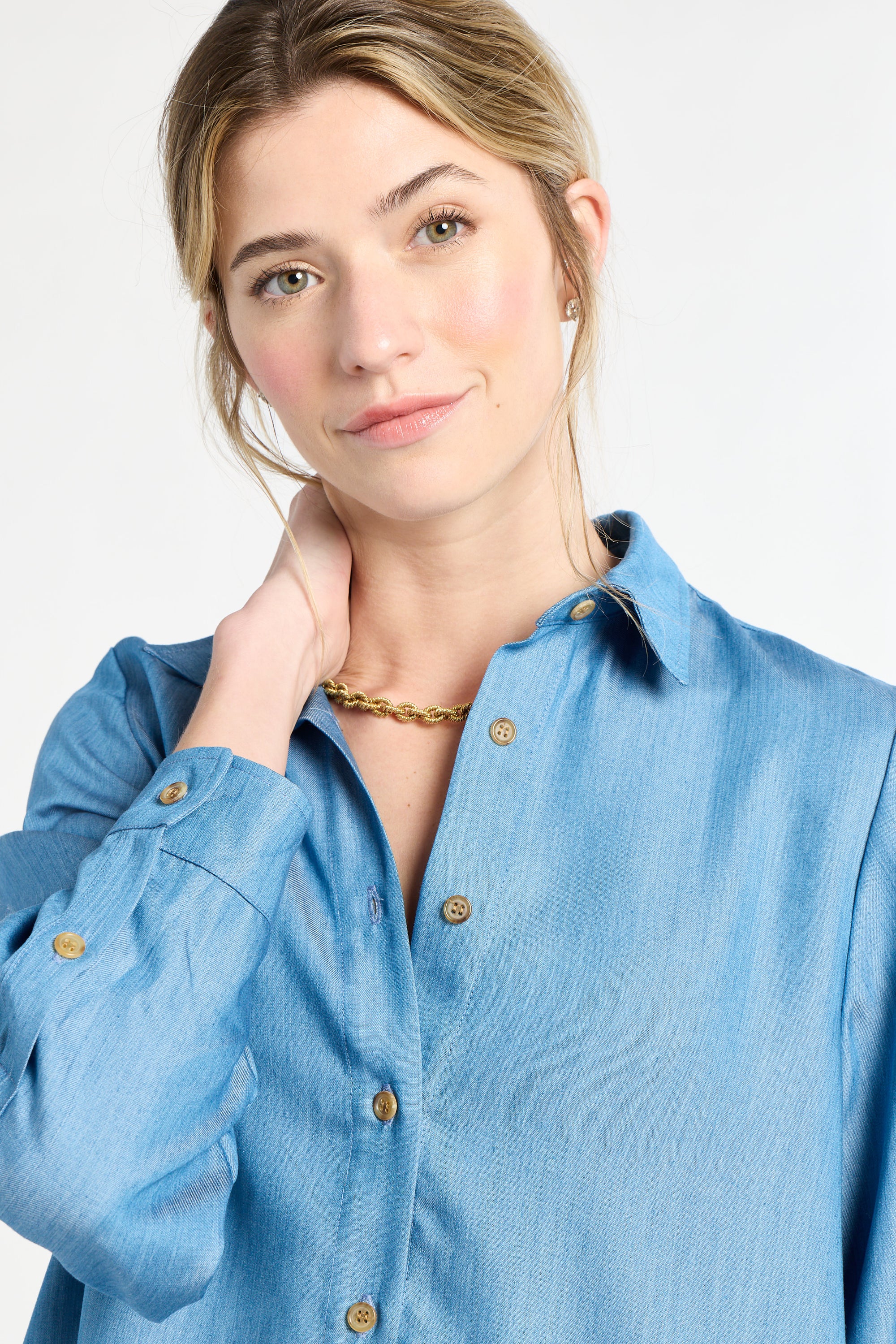 Woman wearing a blue blouse with buttons with a plain white background