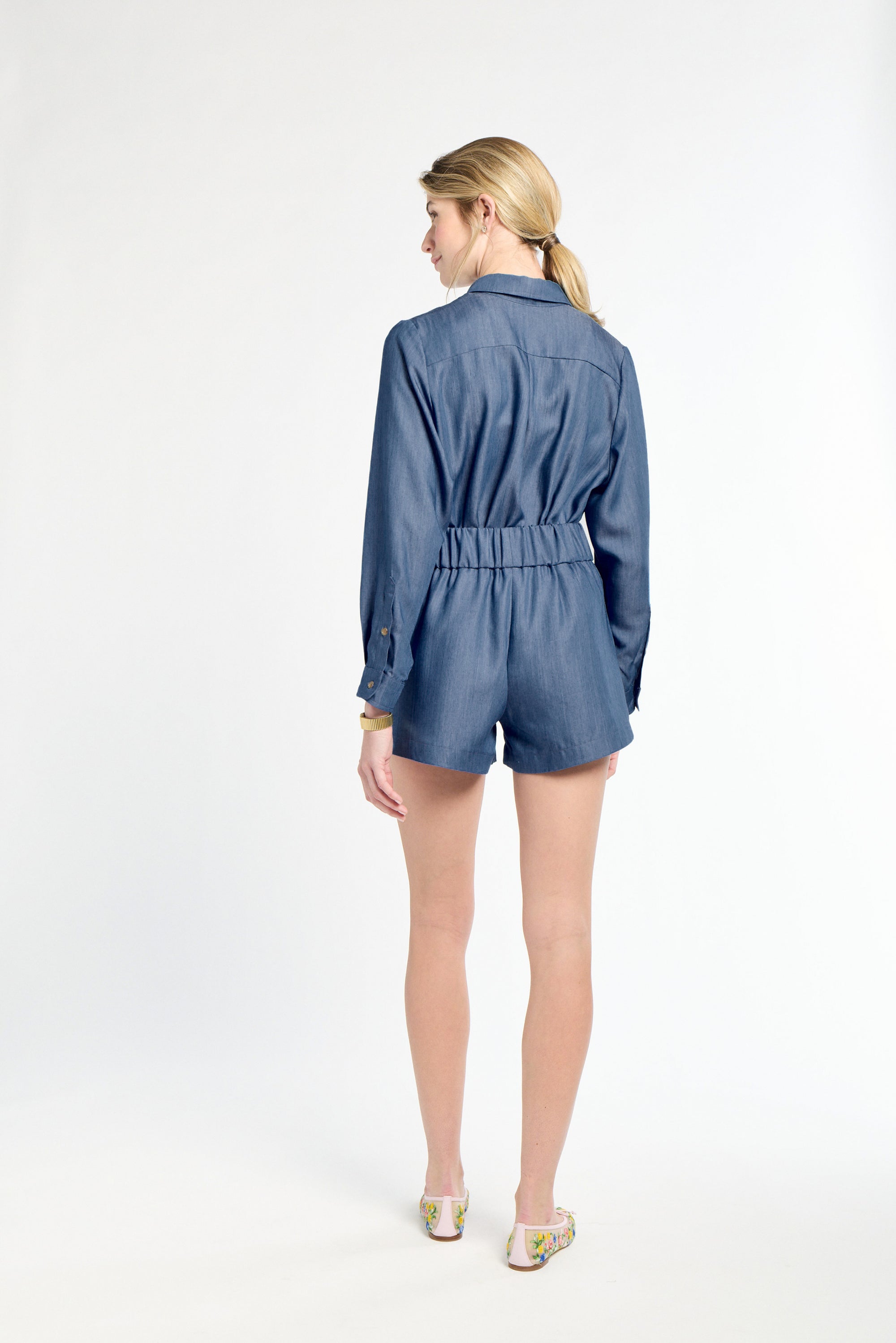 Woman wearing a blue denim romper on a white background