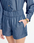 Person wearing a blue denim romper on a white background