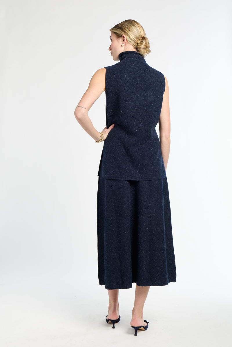 Woman wearing a navy blue sleeveless top and skirt on a white background