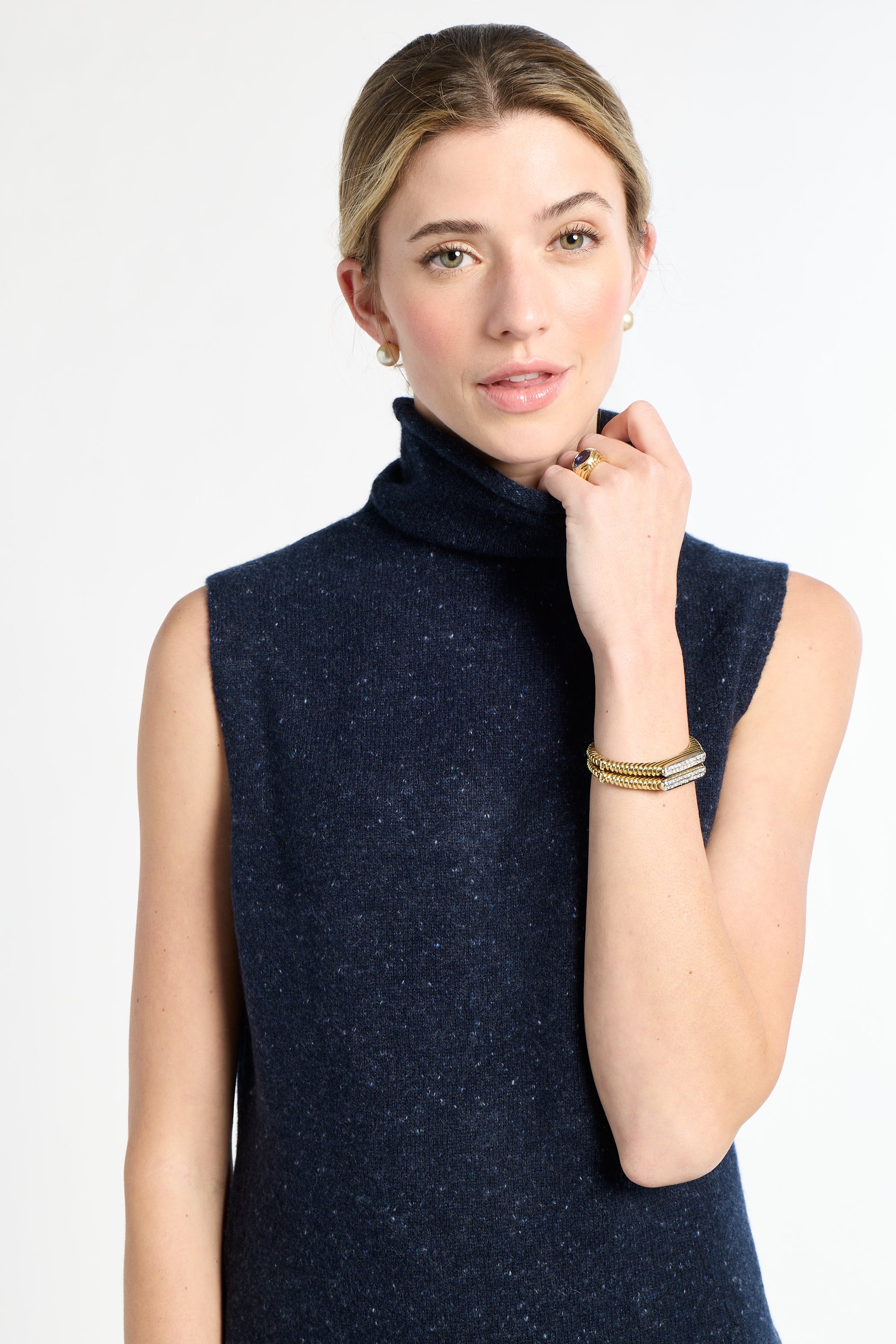 Woman wearing a navy sleeveless sweater against a white background