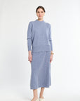Woman wearing a light blue sweater and skirt set on a white background