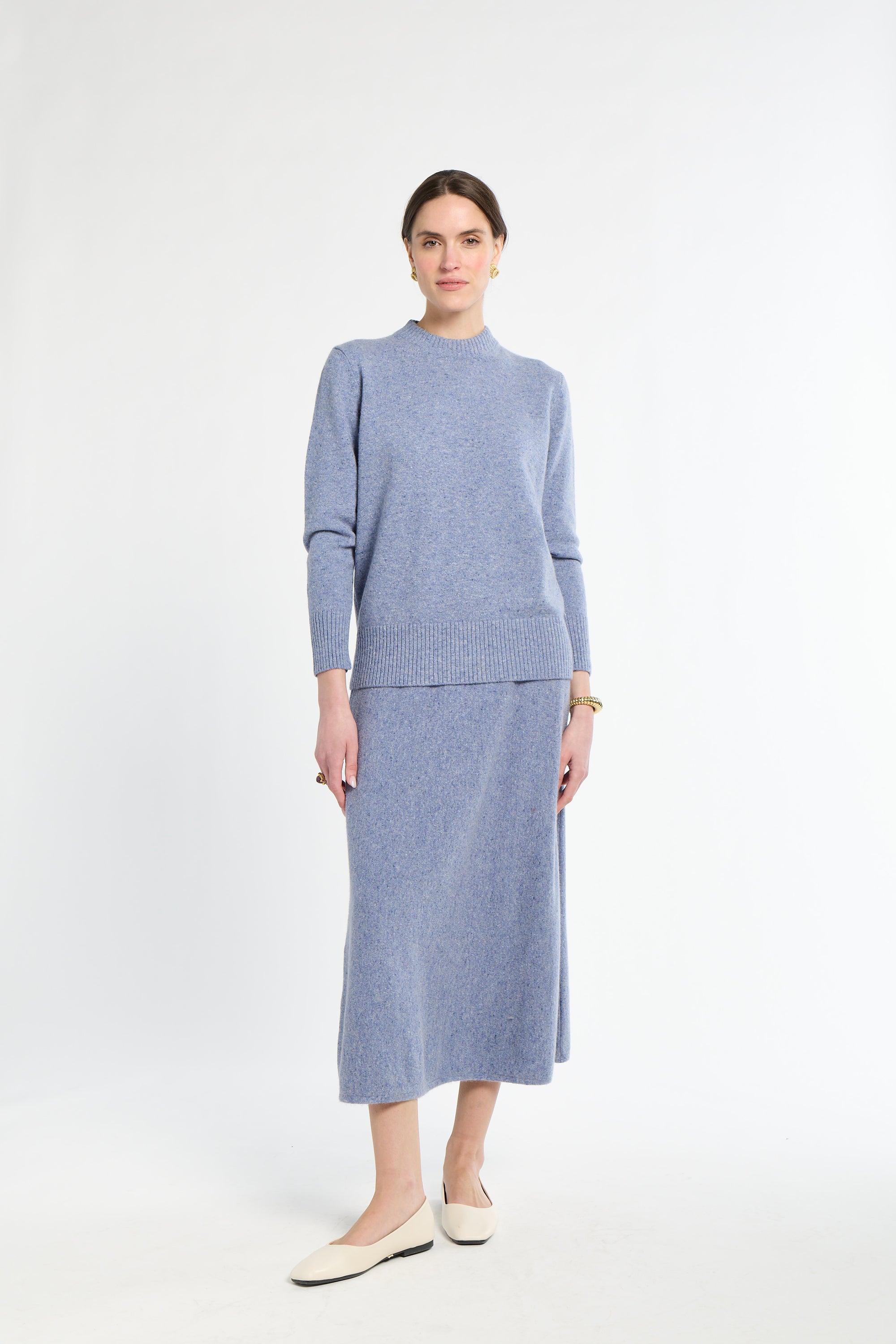 Woman wearing a light blue sweater and skirt set on a white background