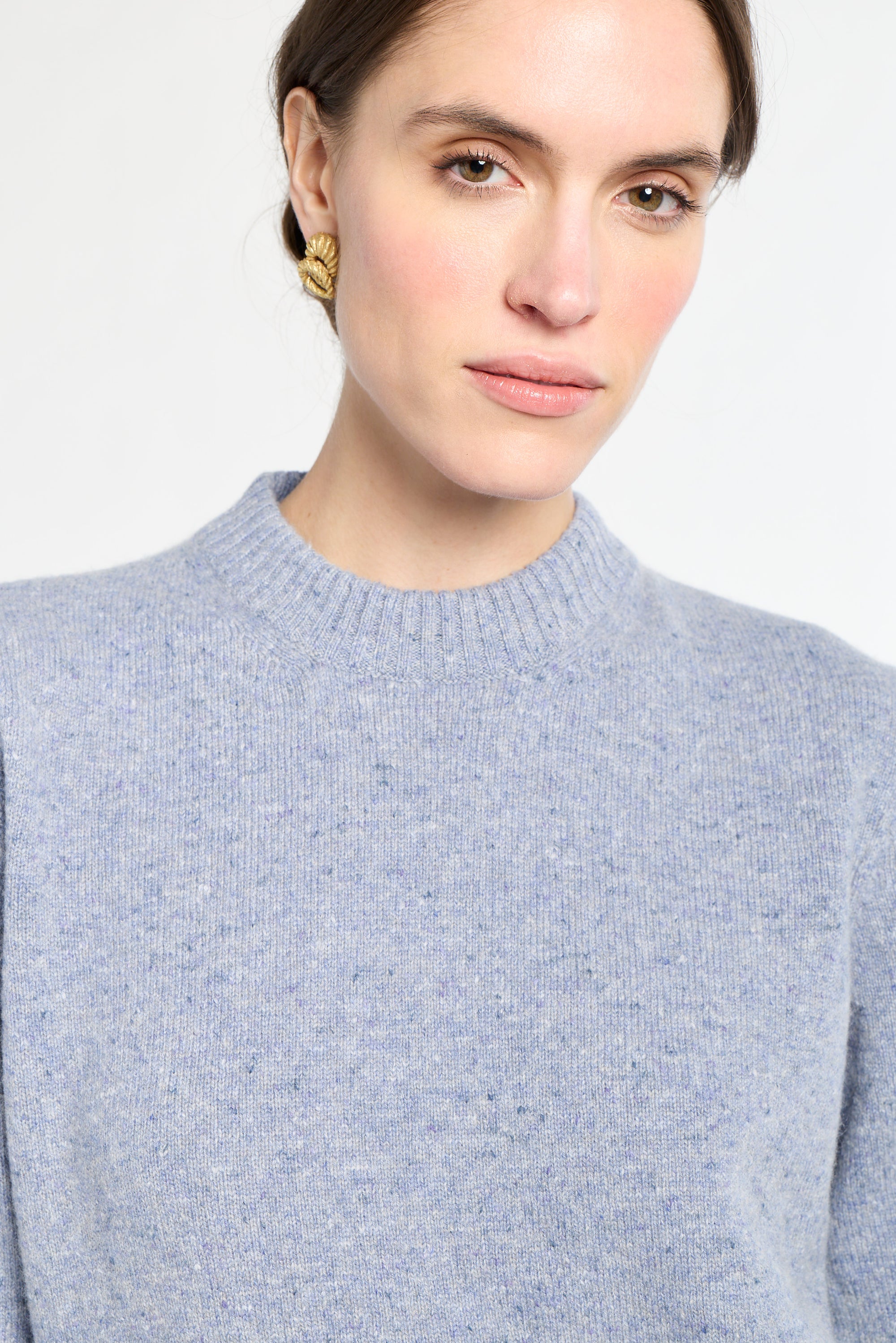 Woman wearing a light blue sweater against a white background
