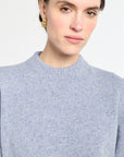 Woman wearing a light blue sweater against a white background