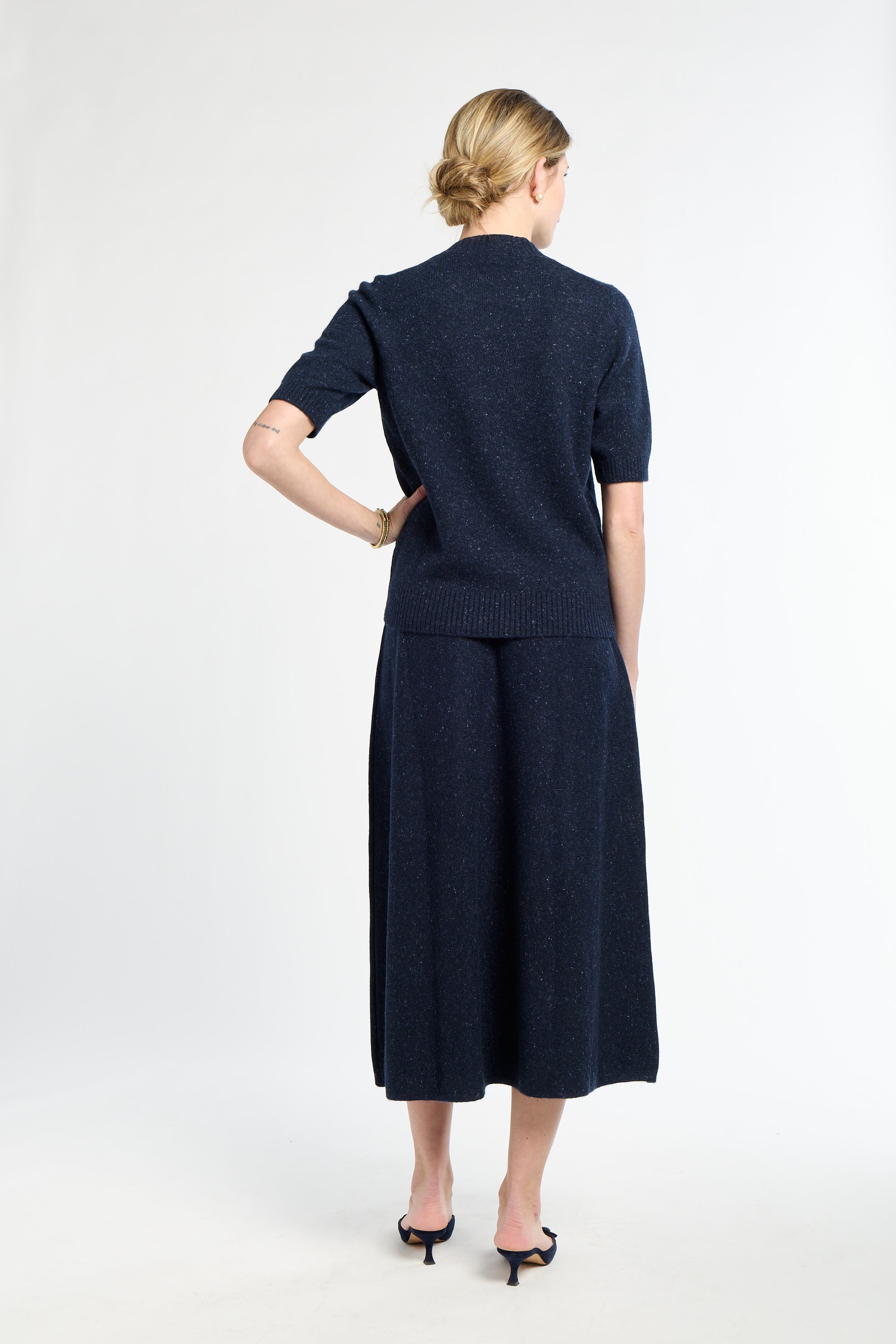 Woman wearing a navy blue outfit with a skirt on a white background